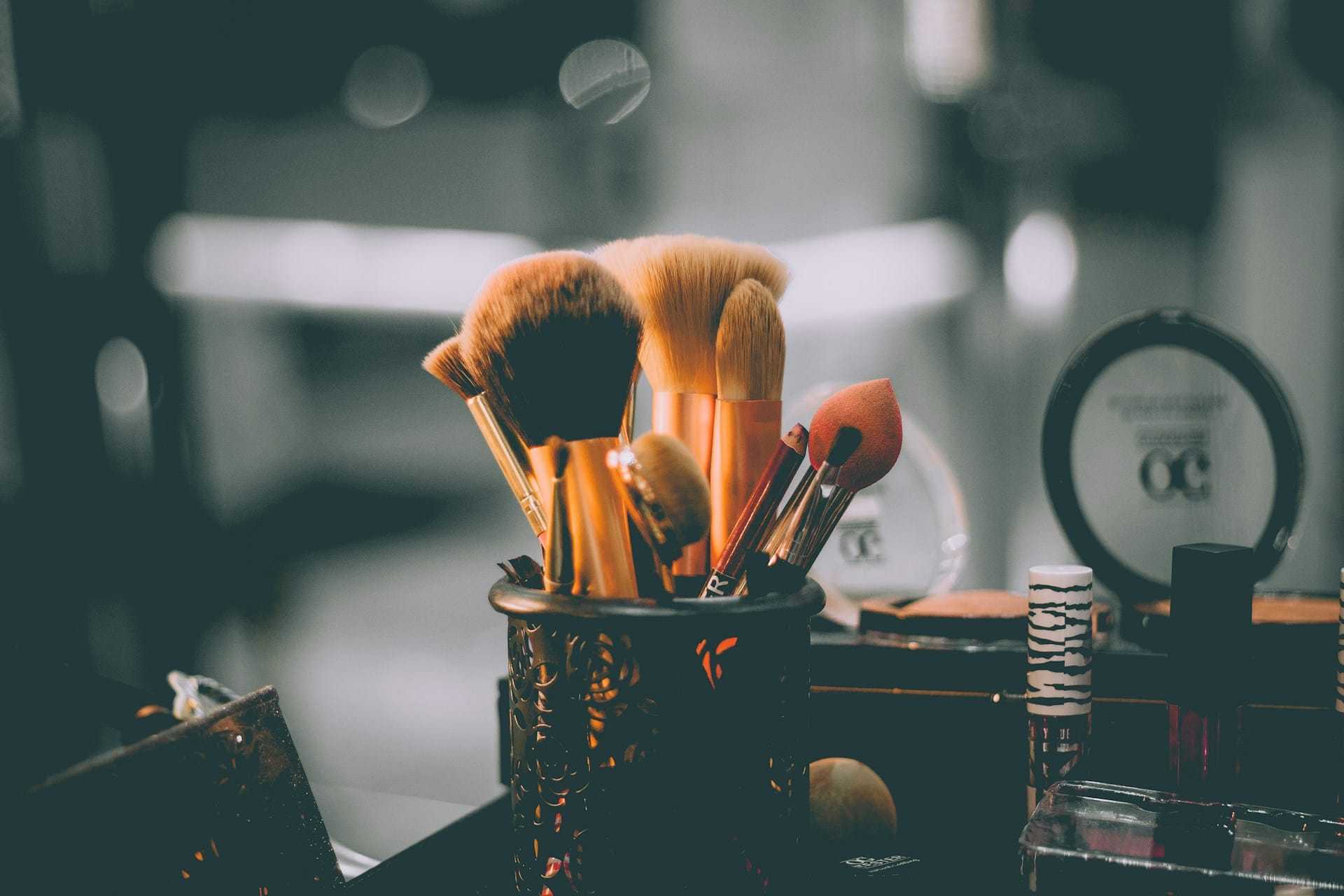 Makeup brushes in a decorative holder on a vanity table.