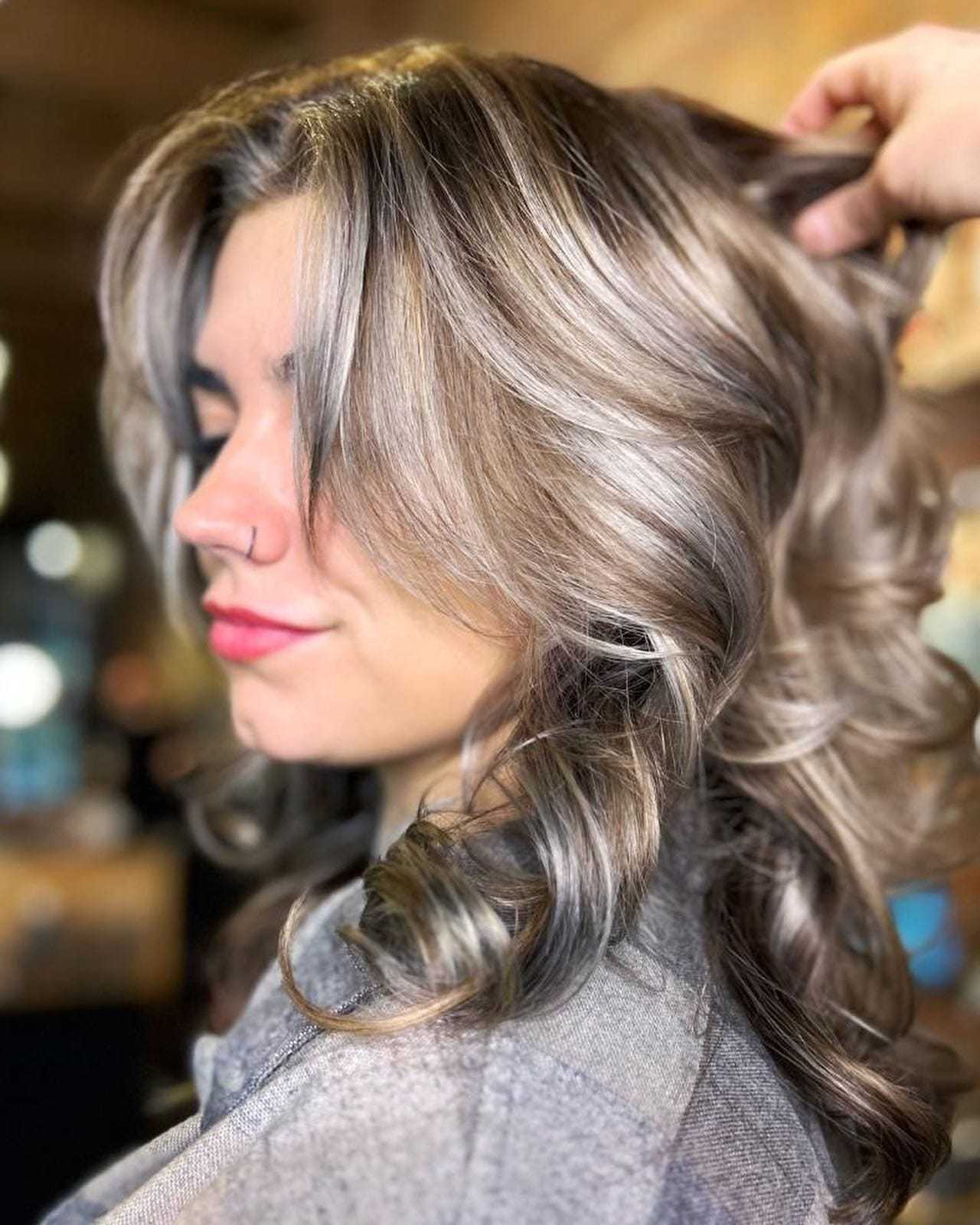 Woman with styled wavy silver-blonde hair in a salon setting.
